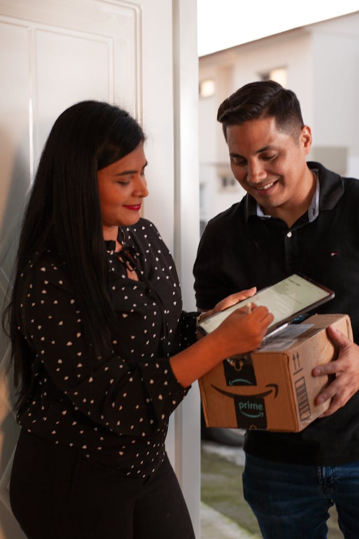 Services A man receives a package from a delivery person who is assisting with a digital signature.